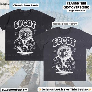 Pu&ograve; includere: Due classiche t-shirt unisex, una nera e una grigia, con una grande grafica bianca di un personaggio sorridente e la scritta "EPCOT" sopra. Il design include "Est. 1982". Le magliette sono etichettate "Classic Tee" e "Original Artist of This Design".