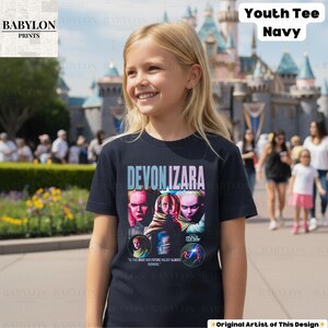 Pu&ograve; includere: T-shirt blu navy per ragazzi con la scritta "DEVON IZARA" e una grafica di tre volti. La maglietta include anche la scritta "MAUL" e "IS THIS WHAT OUR FUTURE HOLDS? ALWAYS RUNNING."