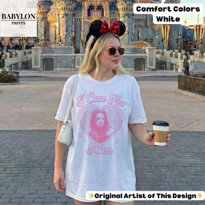 May include: White Comfort Colors t-shirt with a pink heart graphic and the text "I Can Fix Him." The shirt features a portrait and stars. The words "Original Artist of This Design" are at the bottom.