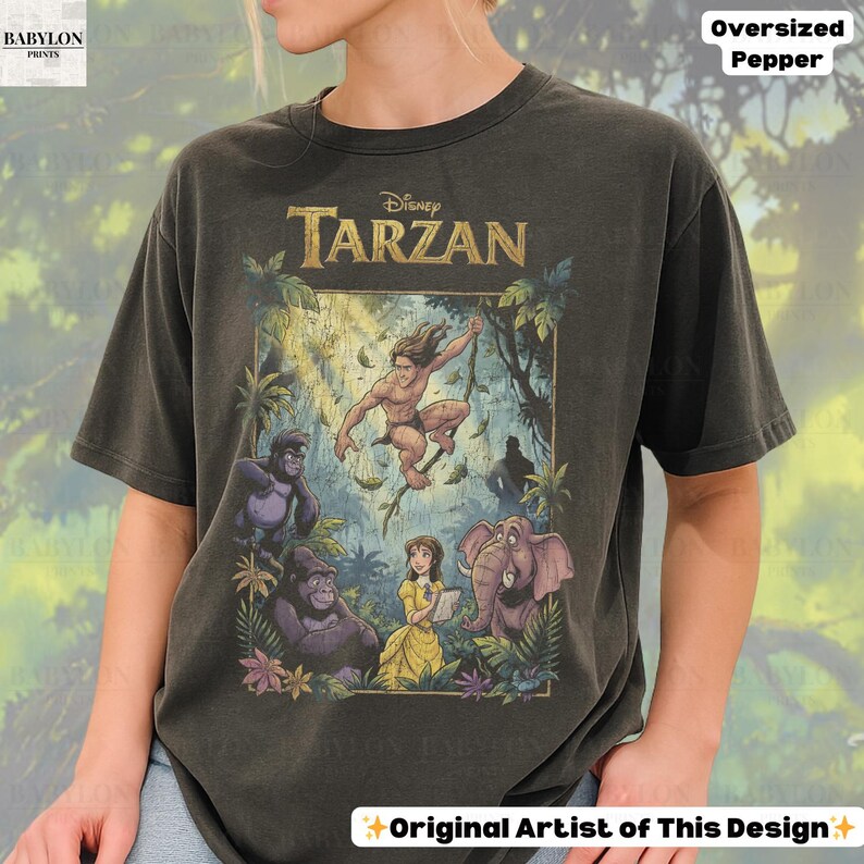 May include: Dark gray oversized t-shirt featuring a colorful graphic from Disney's Tarzan. The design includes Tarzan, gorillas, Jane, and an elephant. The shirt has the text "Disney Tarzan", "Oversized Pepper", and "Original Artist of This Design".