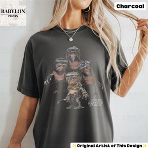 Op de afbeelding: Een antracietgrijs T-shirt met korte mouwen en een grafische print van vier Ewok-personages uit Star Wars. De personages staan in een groep, waarbij er &eacute;&eacute;n op de voorgrond een bril draagt en een gereedschap vasthoudt. Het Star Wars-logo is zichtbaar.