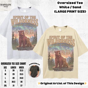 May include: Two oversized t-shirts, one white and one sand-coloured, display a graphic of two bears with the text "Spirit of the Wilderness." The design includes a mountain scene and the words "Brother Bear."