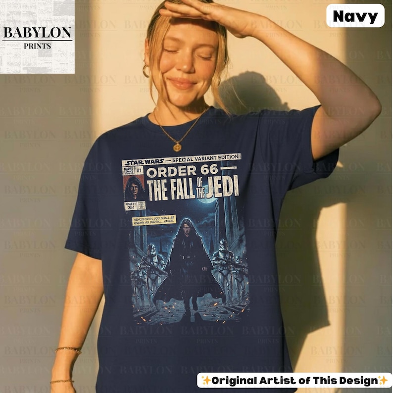 May include: Navy blue t-shirt featuring a comic book-style graphic from Star Wars. The graphic reads "Order 66: The Fall of the Jedi" with illustrations of characters and text. The shirt has short sleeves and a crew neck.