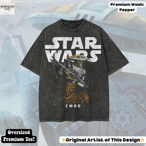 Puede incluir: Camiseta gris oscuro de gran tama&ntilde;o con un gr&aacute;fico de Star Wars. El dise&ntilde;o presenta el texto "STAR WARS" en blanco y una ilustraci&oacute;n del personaje Embo. La camiseta tiene el texto "EMBO" debajo de la ilustraci&oacute;n y "Oversized Premium Tee!" en la parte inferior.