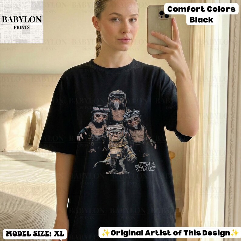Op de afbeelding: Een zwart t-shirt met korte mouwen en een grafische print van vier kleine, harige wezens met grote ogen en een bril. De tekst 'STAR WARS' staat in het wit onder de wezens gedrukt. Het shirt heeft een ronde hals en een relaxte pasvorm.