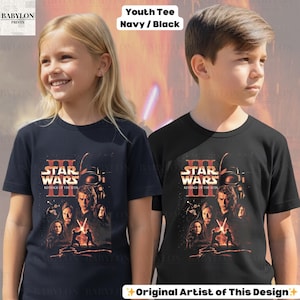 May include: Two youth t-shirts, one navy blue and one black, each featuring a Star Wars III: Revenge of the Sith graphic. The graphic includes characters and the movie title in orange and white. The text "Youth Tee Navy / Black" is at the top.