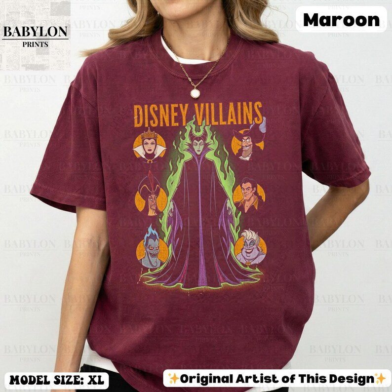 May include: Maroon t-shirt with the text "DISNEY VILLAINS" and illustrations of Disney villains. The shirt has a crew neck. The model is wearing a size XL.