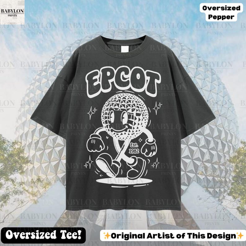 Pu&ograve; includere: T-shirt oversize grigio scuro con la scritta "EPCOT" sopra un personaggio dei cartoni animati di una sfera geodetica sorridente. Il personaggio cammina con un bastone e la scritta "Est. 1982" &egrave; sotto. La maglietta ha il testo "Oversized Tee!" e "Original Artist of This Design" in basso.