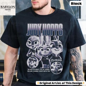 May include: Black t-shirt featuring a graphic of Judy Hopps from Zootopia. The design includes the text "JUDY HOPPS" and the Zootopia logo, along with the quote, "NO MATTER WHAT TYPE OF ANIMAL YOU ARE, CHANGE STARTS WITH YOU." The shirt also has the text "Original Artist of This Design."