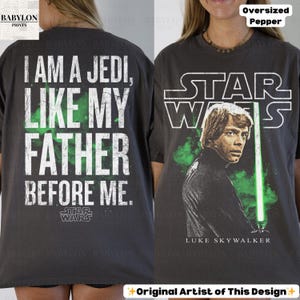 May include: Dark gray oversized t-shirt featuring a Star Wars design. The front displays Luke Skywalker with a green lightsaber and the text "STAR WARS". The back reads "I AM A JEDI, LIKE MY FATHER BEFORE ME."