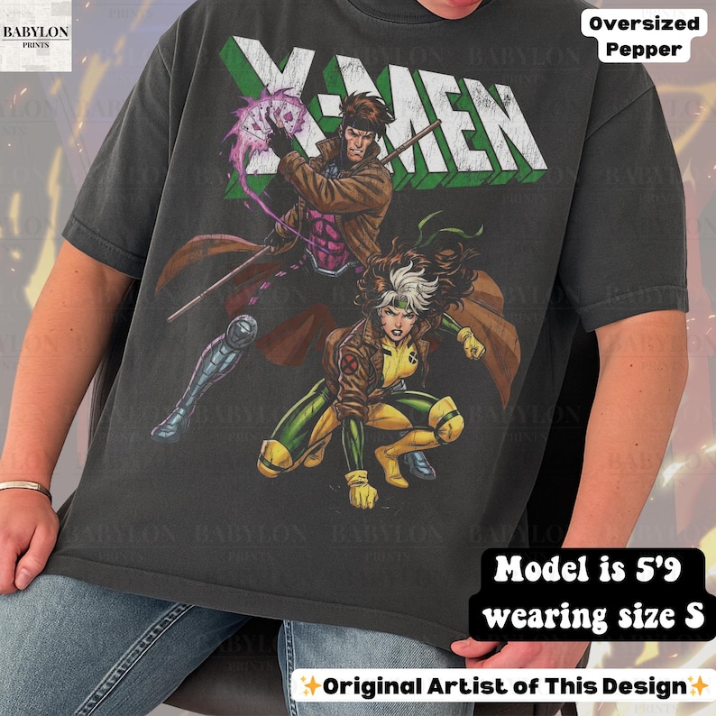 May include: Dark grey oversized t-shirt featuring a graphic of X-Men characters Gambit and Rogue. The word "X-MEN" is printed across the top in white and green. The shirt is a size S and the model is 5'9.