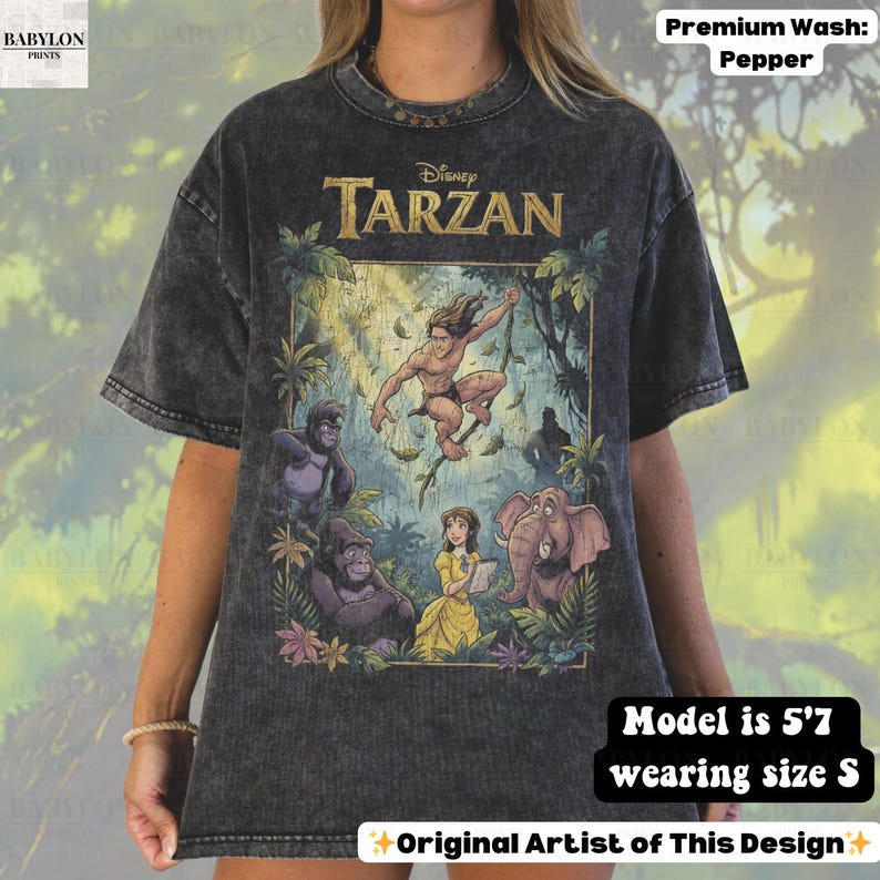 May include: A charcoal gray t-shirt featuring a colorful graphic from Disney's Tarzan. The design includes Tarzan, gorillas, Jane, and an elephant. The shirt has the text "Disney Tarzan" at the top. The shirt is a size S.