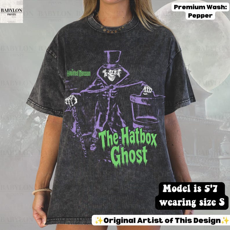 Puede incluir: Una camiseta gris carb&oacute;n con lavado &aacute;cido que presenta un gr&aacute;fico de The Hatbox Ghost de The Haunted Mansion. El dise&ntilde;o incluye al personaje con sombrero de copa, bast&oacute;n y sombrerera, junto al texto The Haunted Mansion y The Hatbox Ghost.