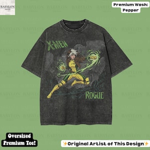 May include: A dark grey oversized t-shirt with a graphic of the X-Men character Rogue in yellow and green. The shirt has the words "X-MEN" and "ROGUE" printed on it. The shirt is labelled "Premium Wash: Pepper" and "Oversized Premium Tee!"