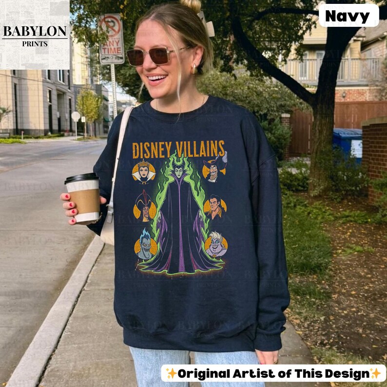 May include: Navy blue sweatshirt with the text "DISNEY VILLAINS" and a graphic of Disney villains. The design includes characters like Maleficent and Ursula. The sweatshirt has long sleeves and a crew neck.