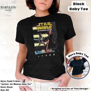 Puede incluir: Camiseta negra juvenil con un gr&aacute;fico de Star Wars: The Phantom Menace. El dise&ntilde;o muestra un duelo de sables de luz. La camiseta es talla XS. El texto "Black Baby Tee" es visible.