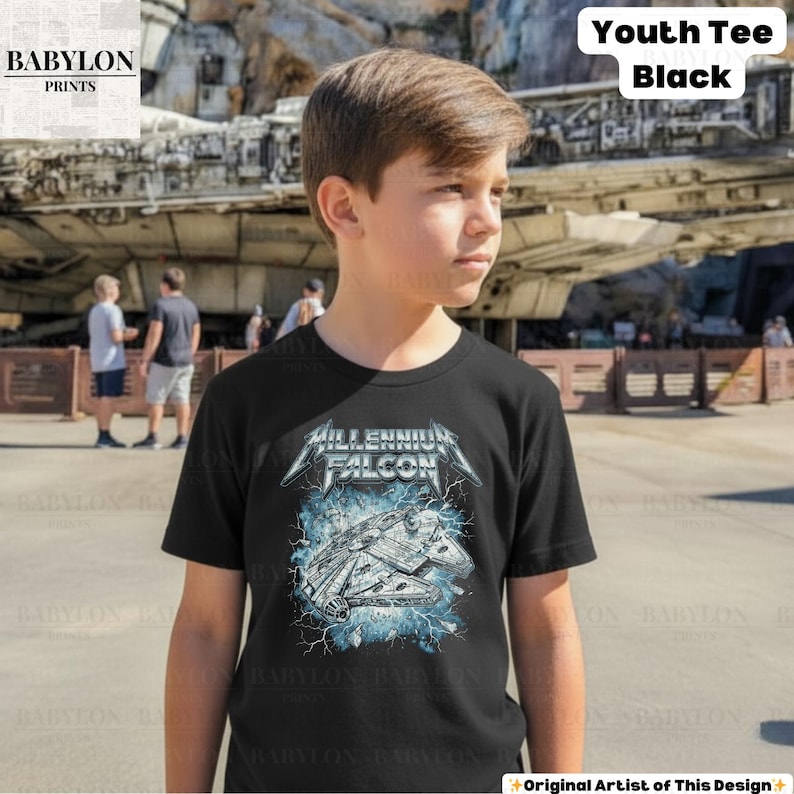 May include: Black youth tee featuring a graphic of the Millennium Falcon spaceship with the text "MILLENNIUM FALCON". The design includes blue lightning effects. The shirt is labeled "Youth Tee Black".