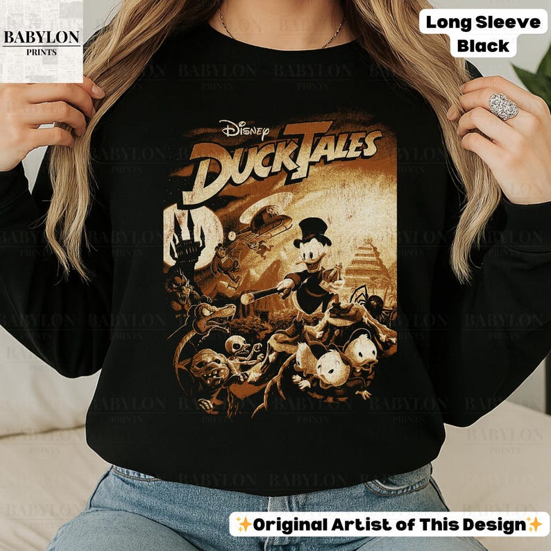 May include: Black long-sleeve sweatshirt featuring a sepia-toned graphic from Disney's DuckTales. The design includes Donald Duck, the title logo, and various characters. The text "Long Sleeve Black" is visible.
