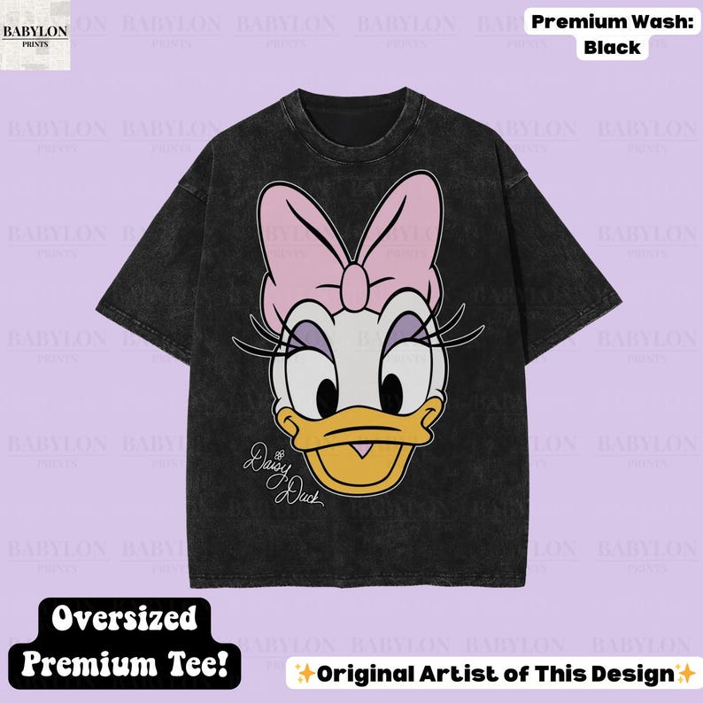 Puede incluir: Camiseta negra de gran tama&ntilde;o de primera calidad con un gr&aacute;fico de Daisy Duck. El dise&ntilde;o incluye un lazo rosa, pesta&ntilde;as y el texto "Daisy Duck". La camiseta tiene un lavado de primera calidad y el texto "Original Artist of This Design".