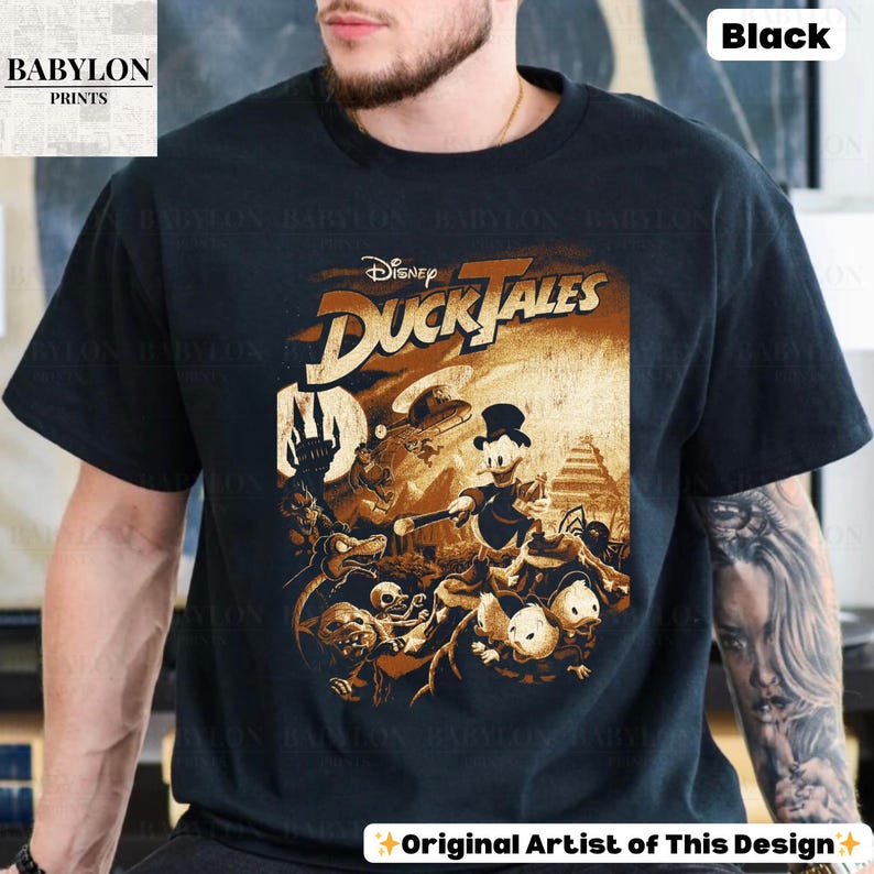 May include: Black t-shirt featuring a vintage-style graphic from Disney's DuckTales. The design includes Donald Duck and other characters in a sepia-toned illustration. The shirt also has the text "BABYLON PRINTS" and "Original Artist of This Design".