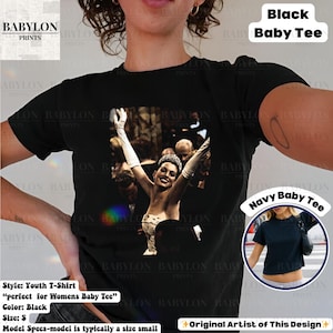May include: Black youth t-shirt with a black and white image of a woman with her arms raised. The shirt has the text "Black Baby Tee" printed on it. The shirt is a size small.