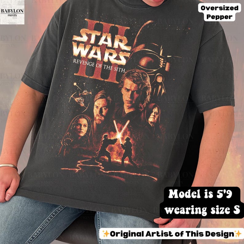 May include: Dark gray t-shirt featuring a Star Wars: Revenge of the Sith graphic. The design includes characters like Darth Vader, Anakin Skywalker, and Obi-Wan Kenobi. The shirt is oversized and the model is 5'9 wearing size S.