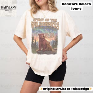 May include: Ivory t-shirt featuring the text "Spirit of the Wilderness" and a graphic of two bears. The shirt also has the text "Brother Bear" and "Northern Adventure". Made of Comfort Colors material.