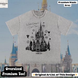 May include: Grey oversized premium tee with a black and white castle illustration and the text "Where Dreams Come True." The design includes Mickey Mouse silhouettes and fireworks. The shirt is made of a soft, comfortable material.