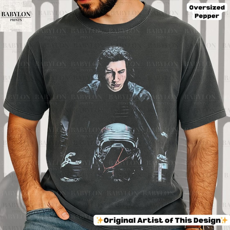 May include: Dark grey oversized t-shirt with a portrait of a person and a helmet. The shirt has the text "BABYLON PRINTS" and "Original Artist of This Design".