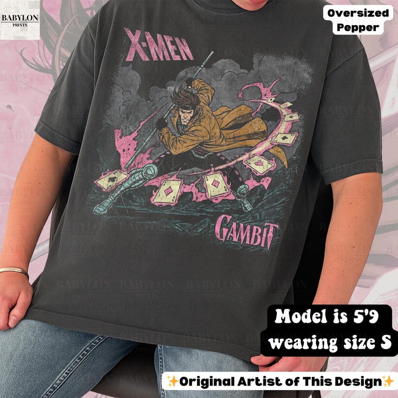May include: Dark gray oversized t-shirt featuring a graphic of the X-Men character Gambit. The design includes the character in a dynamic pose with playing cards and the text "X-MEN" and "GAMBIT" in pink. The shirt is a size S.