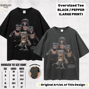 Op de afbeelding: Twee oversized t-shirts in zwart en pepergrijs met een grafische print van vier Ewok-personages uit Star Wars. De shirts hebben korte mouwen en een ronde hals. Een maattabel is inbegrepen met afmetingen in inches voor de maten S tot 2XL.