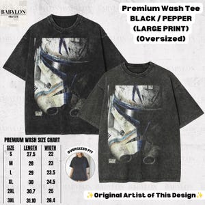 May include: An oversized black and pepper premium wash t-shirt featuring a large graphic print of a weathered white and blue clone trooper helmet. The shirt includes the text Premium Wash Tee BLACK / PEPPER (LARGE PRINT) (OVERSIZED).