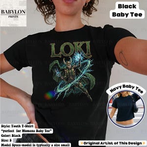 May include: Black youth t-shirt featuring the word "LOKI" in green lettering above a graphic of a character with blue and green energy effects. The shirt has short sleeves and is labeled "Black Baby Tee."