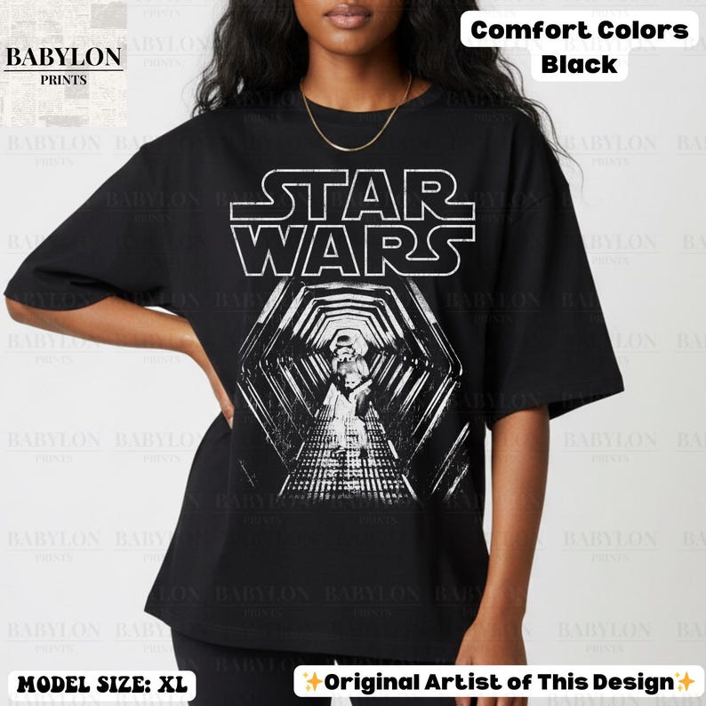 May include: Black t-shirt featuring the Star Wars logo and a Stormtrooper in a tunnel design. The shirt is made of Comfort Colors material. The model is wearing size XL.