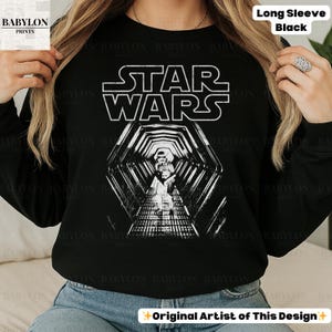 May include: Black long-sleeve shirt featuring the Star Wars logo in white, with a detailed graphic of a tunnel scene. The text "Long Sleeve Black" is at the top right. The shirt is from Babylon Prints.