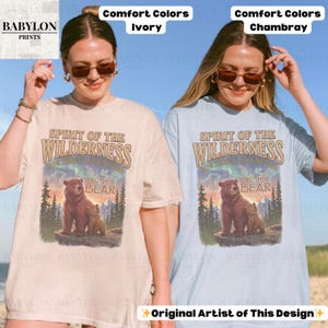 May include: Two t-shirts, one ivory and one chambray, with a graphic of a bear family in a wilderness setting. The text on the shirts reads "Spirit of the Wilderness" and "Brother Bear."