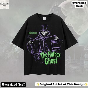 Puede incluir: Una camiseta negra de corte oversize con un estampado gr&aacute;fico de The Hatbox Ghost de The Haunted Mansion. El dise&ntilde;o muestra al personaje con sombrero de copa y abrigo, sosteniendo una sombrerera, con el texto The Haunted Mansion y The Hatbox Ghost.