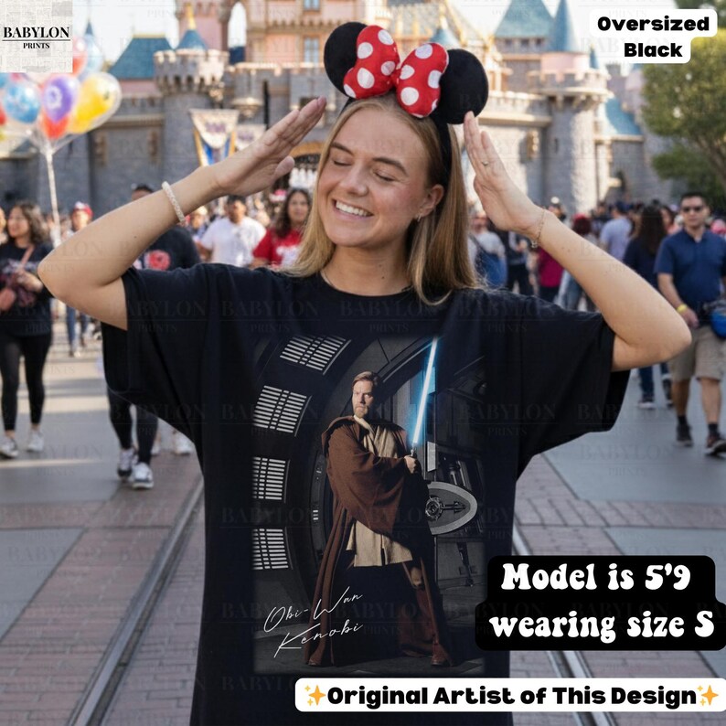 Może przedstawiać: Czarny, duży t-shirt z Obi-Wanem Kenobim i mieczem świetlnym. Koszulka ma napis "Obi-Wan Kenobi" i "Original Artist of This Design". Modelka ma 175 cm wzrostu i nosi rozmiar S.