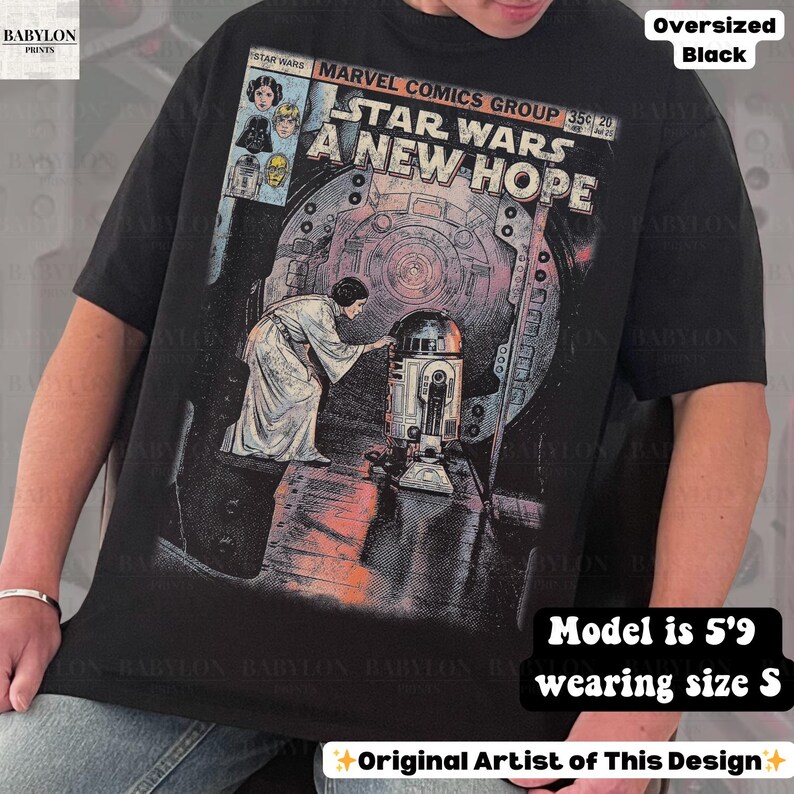 May include: Black oversized t-shirt featuring a comic book cover design from Star Wars: A New Hope. The graphic includes Princess Leia and R2-D2, with the Marvel Comics Group logo. The shirt also has the text "Original Artist of This Design."