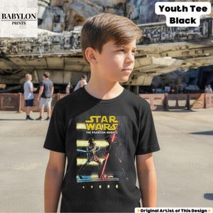 Puede incluir: Camiseta negra juvenil con un gr&aacute;fico de Star Wars: La Amenaza Fantasma. El dise&ntilde;o incluye el t&iacute;tulo de la pel&iacute;cula y personajes con sables de luz. La camiseta est&aacute; etiquetada como "Youth Tee Black" y es de Babylon Prints.