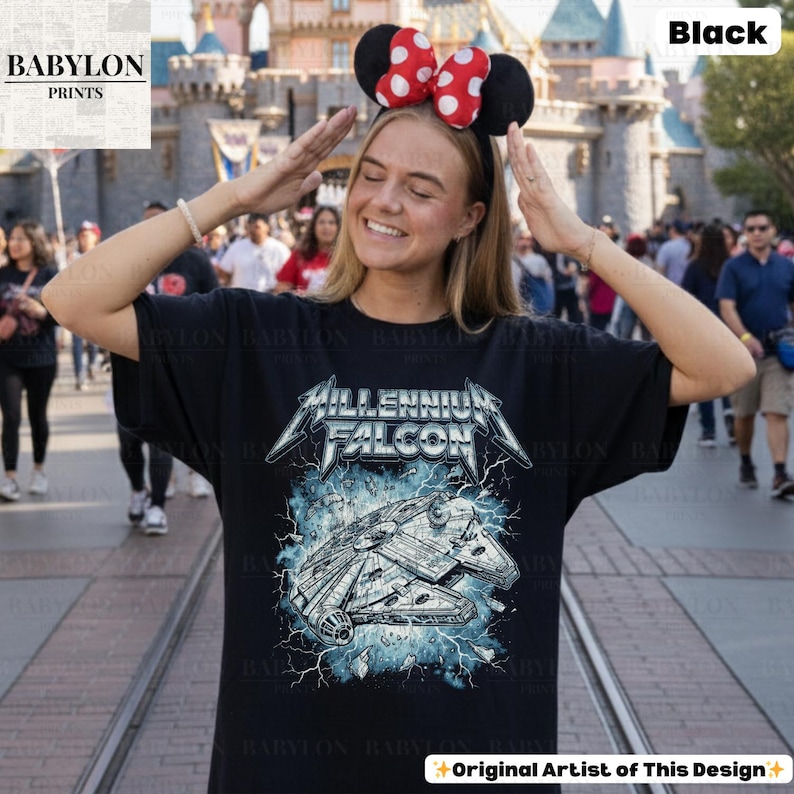 May include: Black t-shirt featuring a graphic of the Millennium Falcon spaceship with the text "MILLENNIUM FALCON" in a stylized font. The design includes blue lightning effects. The shirt is worn by a person wearing a Minnie Mouse ear headband.