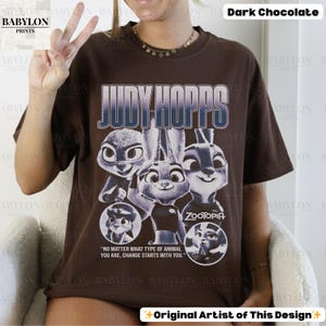 May include: Dark chocolate brown t-shirt featuring the text "JUDY HOPPS" above a graphic of characters from the movie Zootopia. The shirt also includes the quote, "NO MATTER WHAT TYPE OF ANIMAL YOU ARE, CHANGE STARTS WITH YOU."