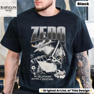 May include: Black t-shirt featuring a graphic from "The Nightmare Before Christmas" with the word "ZERO" in large letters. The design includes images of Zero, Jack Skellington, and other characters from the movie. The shirt also has the text "Original Artist of This Design".
