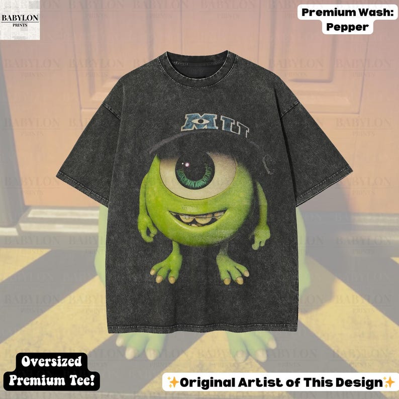 K&ouml;nnte beinhalten: Dunkelgraues, &uuml;bergro&szlig;es Premium-T-Shirt mit einer Cartoonfigur mit einem gro&szlig;en gr&uuml;nen Auge, die einen Hut mit den Buchstaben "MIT" tr&auml;gt. Das Shirt tr&auml;gt den Text "Premium Wash: Pepper" und "Oversized Premium Tee!"
