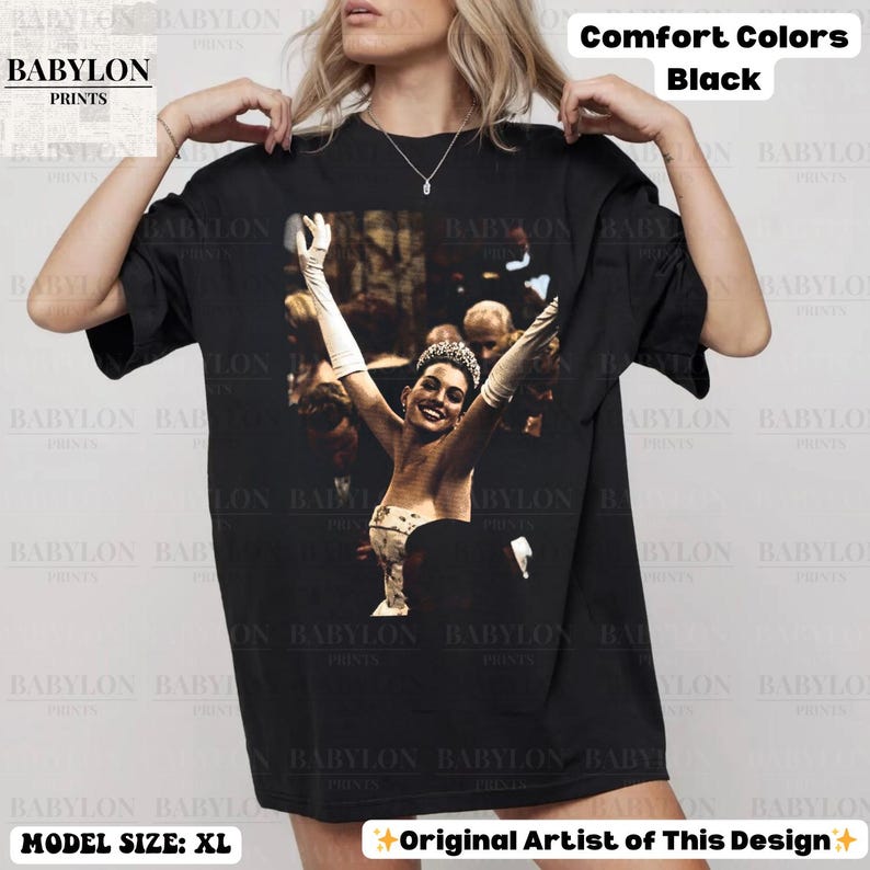 May include: Black Comfort Colors t-shirt with a graphic of a woman with her arms raised. The shirt has the text "BABYLON PRINTS" and "Original Artist of This Design". Model size is XL.