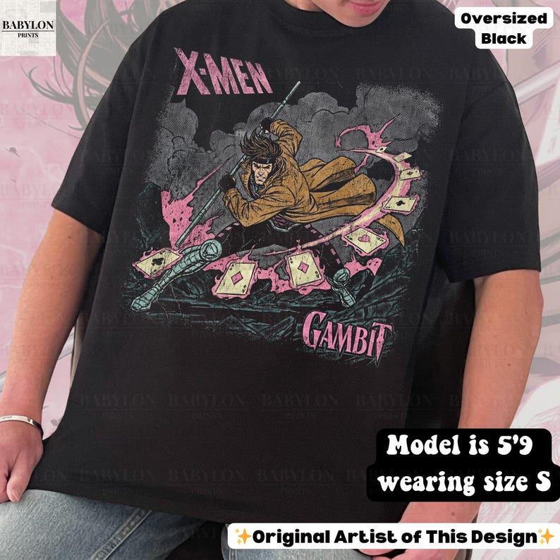 May include: Black oversized t-shirt featuring a graphic of the X-Men character Gambit. The design includes the character wielding a staff and playing cards. The shirt has the words "X-MEN" and "GAMBIT" printed on it.