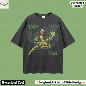 May include: Dark grey oversized t-shirt with a graphic of the X-Men character Rogue, depicted in a dynamic pose with green energy effects. The shirt features the text "X-MEN" and "ROGUE" in green.