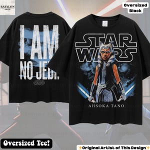 May include: Black oversized tee shirt featuring a Star Wars design. The front displays Ahsoka Tano with lightsabers and the text "STAR WARS". The back has the text "I AM NO JEDI." in white. The shirt is a comfortable oversized fit.