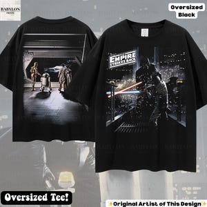 May include: Black oversized tee shirt featuring scenes from "The Empire Strikes Back." The front of the shirt displays a battle scene with lightsabers, while the back shows characters in a hallway. The shirt has the text "The Empire Strikes Back."