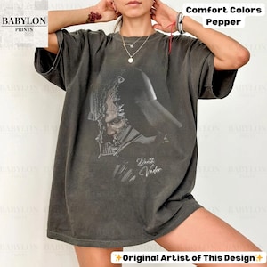 K&ouml;nnte beinhalten: Ein dunkelgraues Comfort Colors T-Shirt mit einer Grafik von Darth Vader. Das Bild enth&auml;lt den Text "Darth Vader". Das Shirt tr&auml;gt auch die Aufschrift "Comfort Colors Pepper" und "Original Artist of This Design".